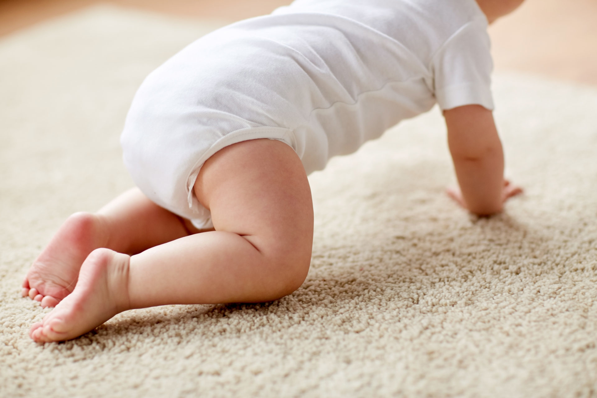 childhood, babyhood and people concept - little baby boy or girl crawling on floor at home